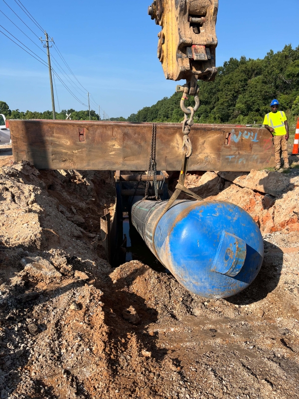 A crew uses heavy machinery to align a segment of carrier pipe with the forcemain.