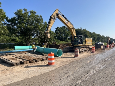 A crew uses heavy machinery to move a section of the slipline carrier pipe