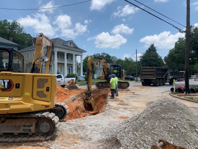 Crew members dig into the road to expose existing pipes.